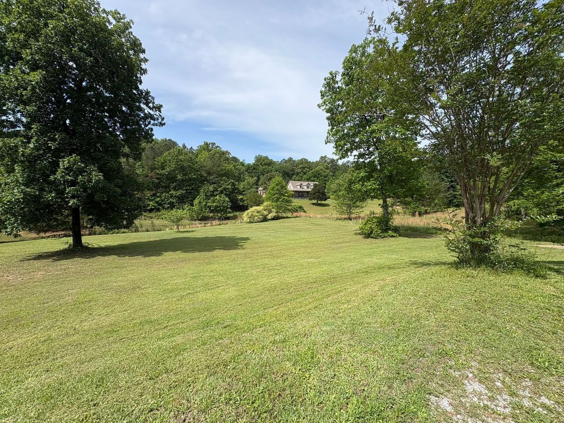 Wide freshly mowed acreage with a pond and home on the hill near Gadsden, Alabama