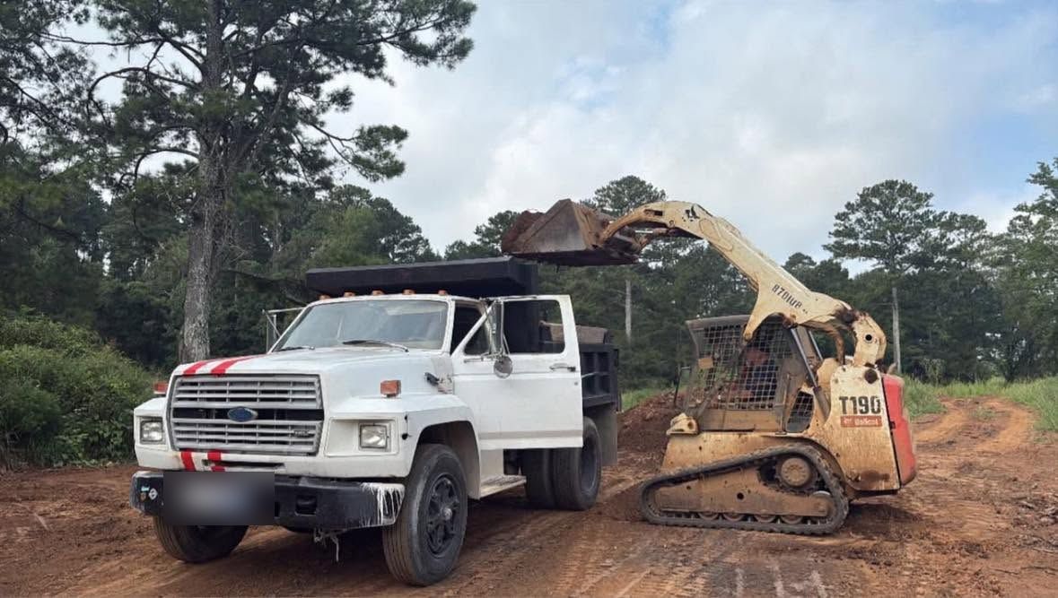 Bobcat skid steer loading dirt into a dump truck