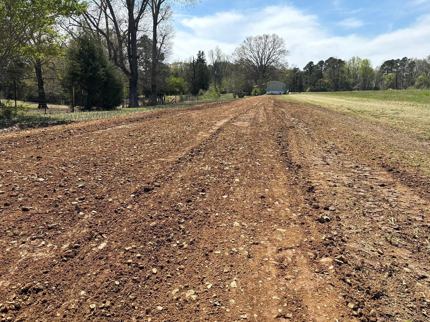 Freshly graded dirt road running toward a home