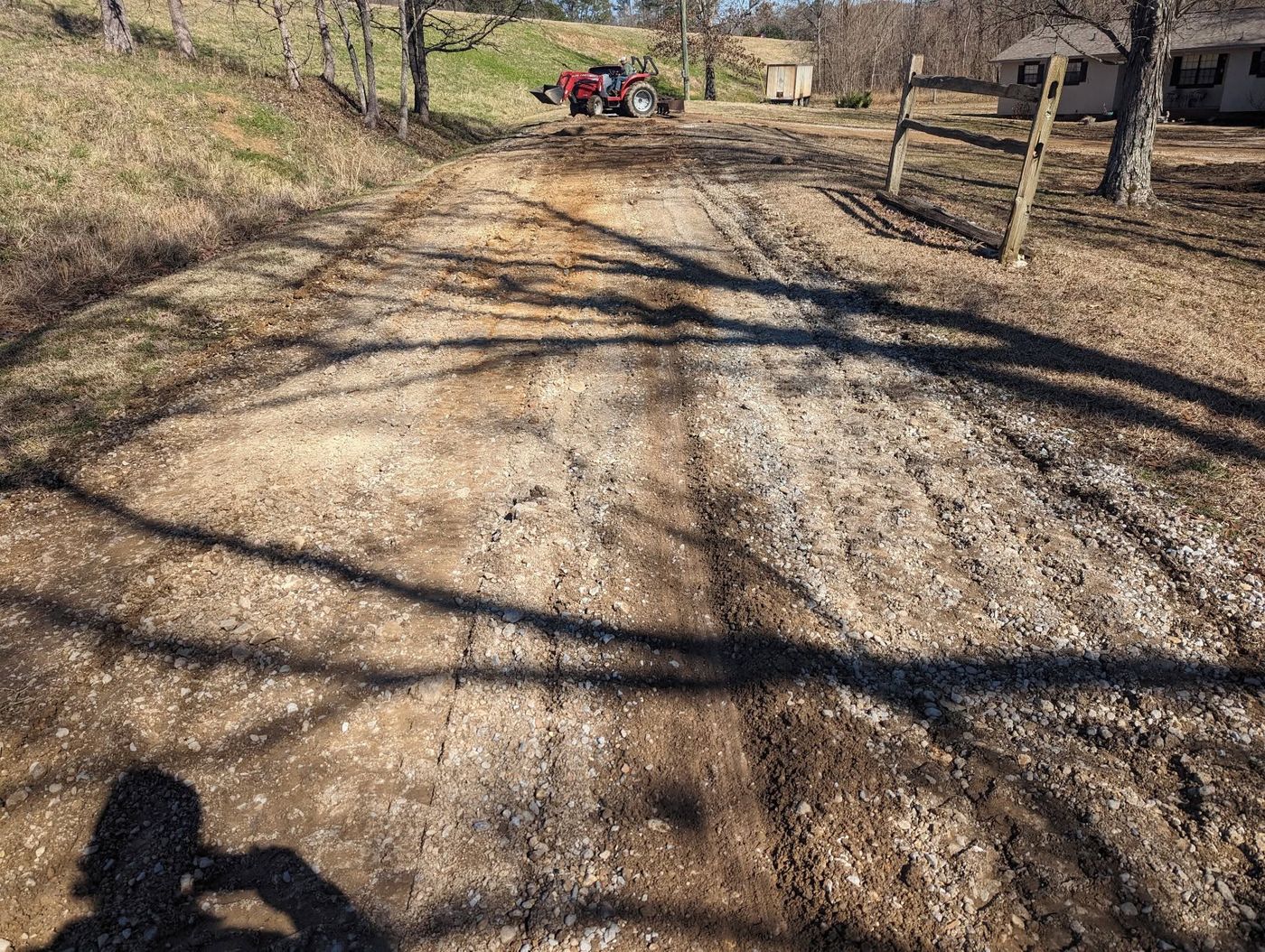 Potholed washed out gravel driveway before repair