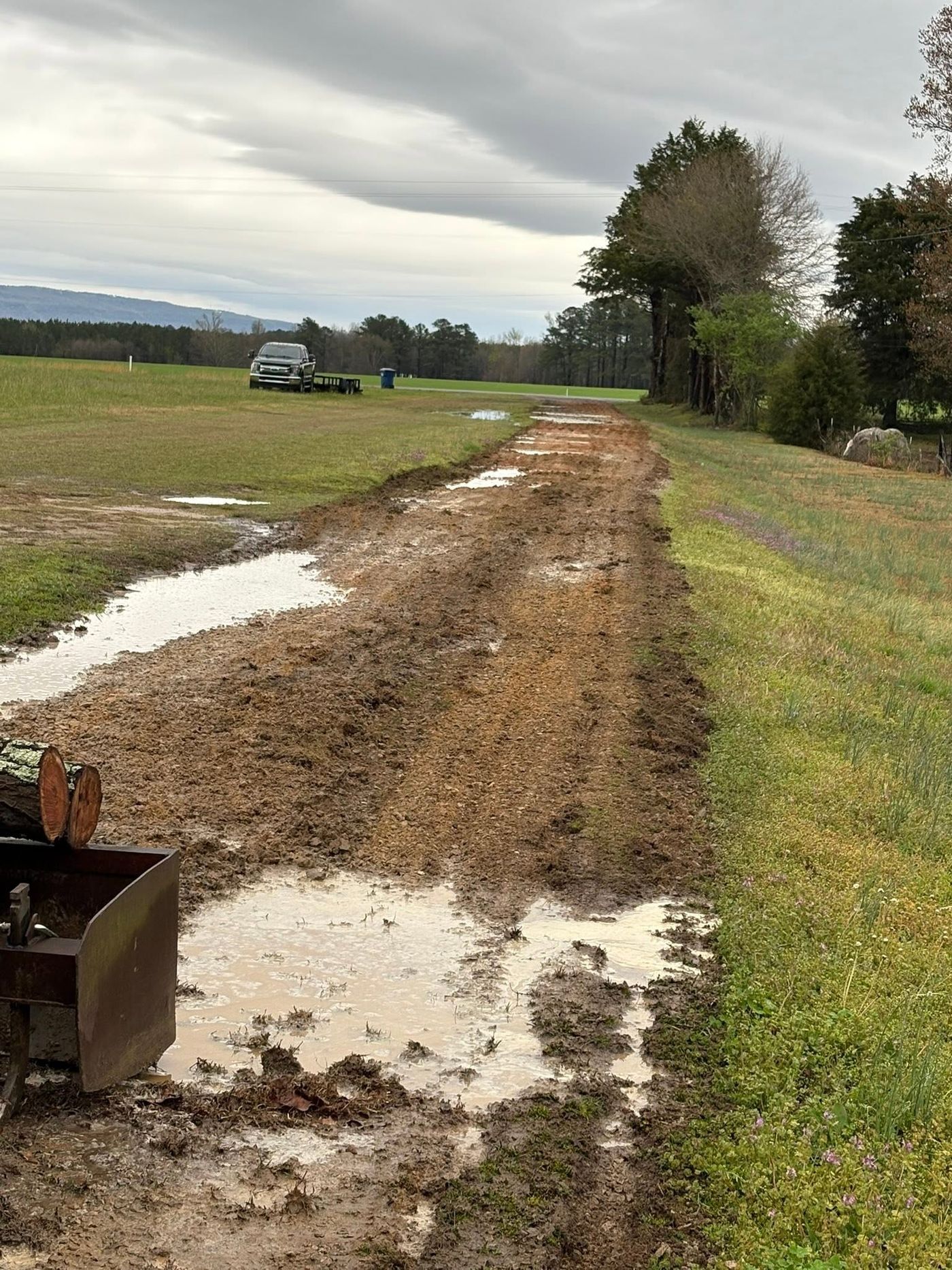 Rutted muddy farm drive with standing water before grading