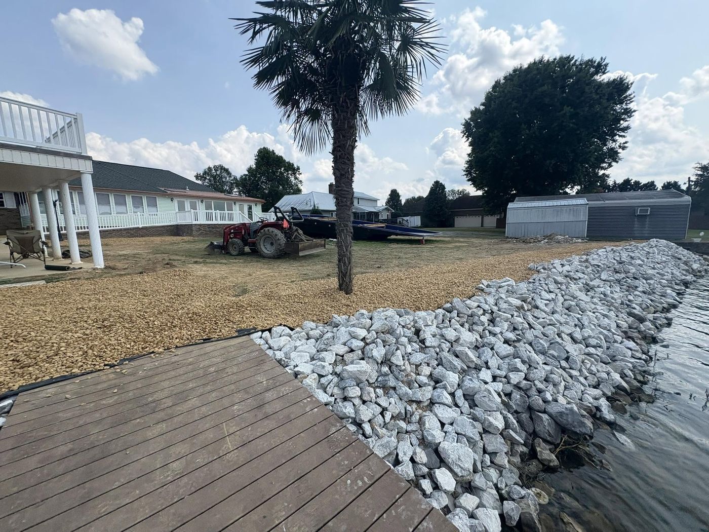 River rock bed behind rip-rap with tractor on site