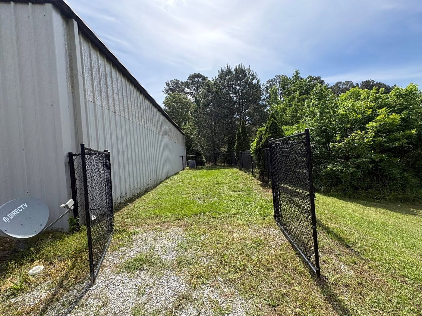 Mowed strip beside a metal shop building and gate